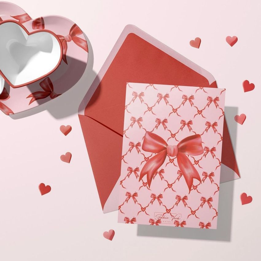 Paper valentines card mockup featuring a red bow pattern on a pink card, paired with a red envelope and heart-shaped props.