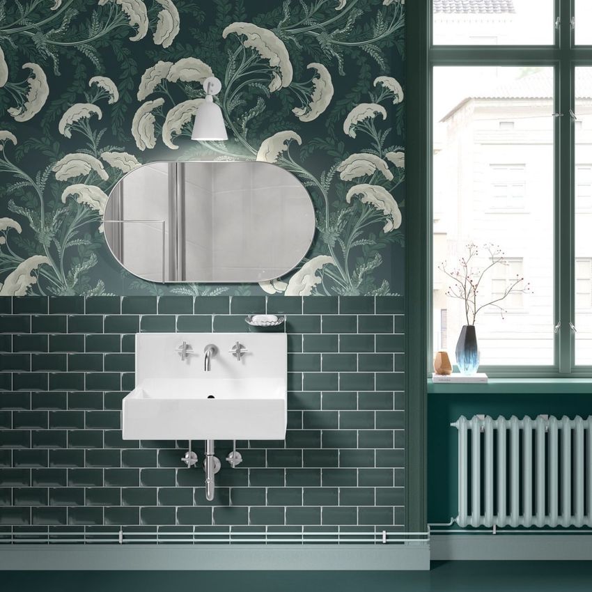Vintage bathroom mockup showing a white sink, green subway tile, and leafy patterned wallpaper with an oval mirror above.