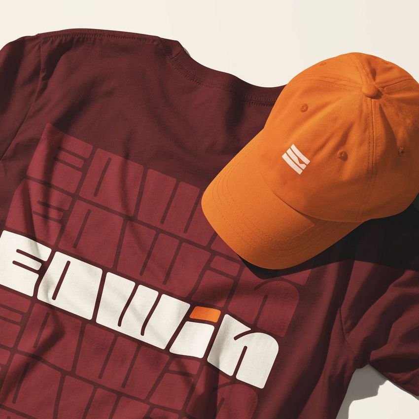 T-shirt and cap mockup featuring a maroon shirt with bold geometric text and an orange cap with a simple white logo on top.