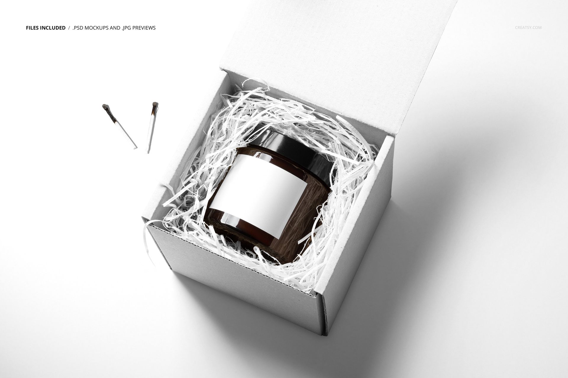 Amber jar candle mockup in a white box with shredded paper, shown from a high angle on a bright background.