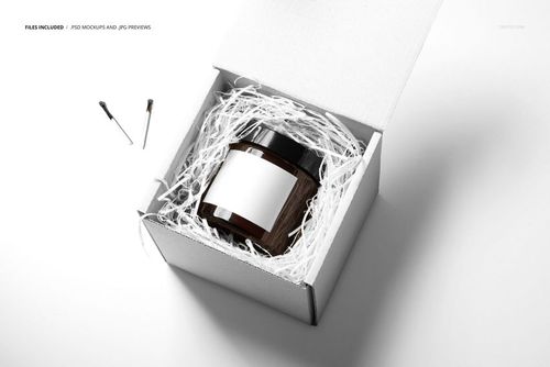 Amber jar candle mockup in a white box with shredded paper, shown from a high angle on a bright background.