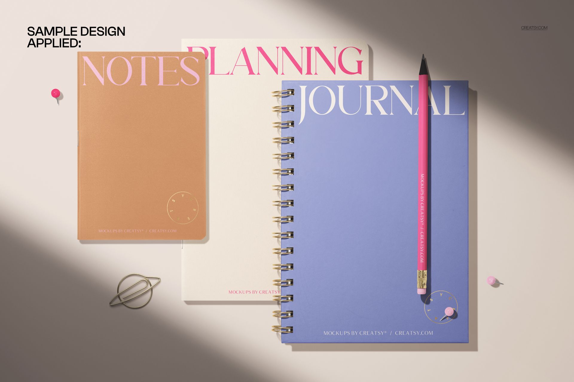 Stationery mockup featuring a spiral-bound journal, softcover notebook, and pencil, viewed from above on a light background.