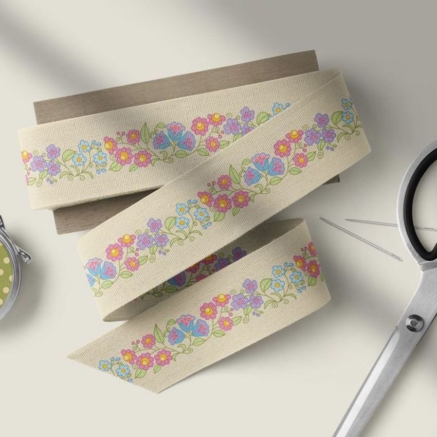 Cotton ribbon mockup featuring a folk-inspired floral pattern in pink, blue, and yellow, arranged on a neutral surface.