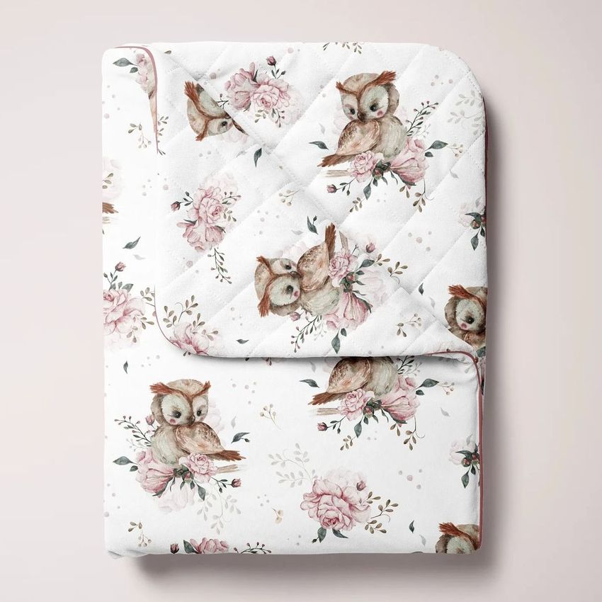 Double-sided baby bedding set mockup showing a folded quilt with watercolor owls and pink floral patterns on a light background.