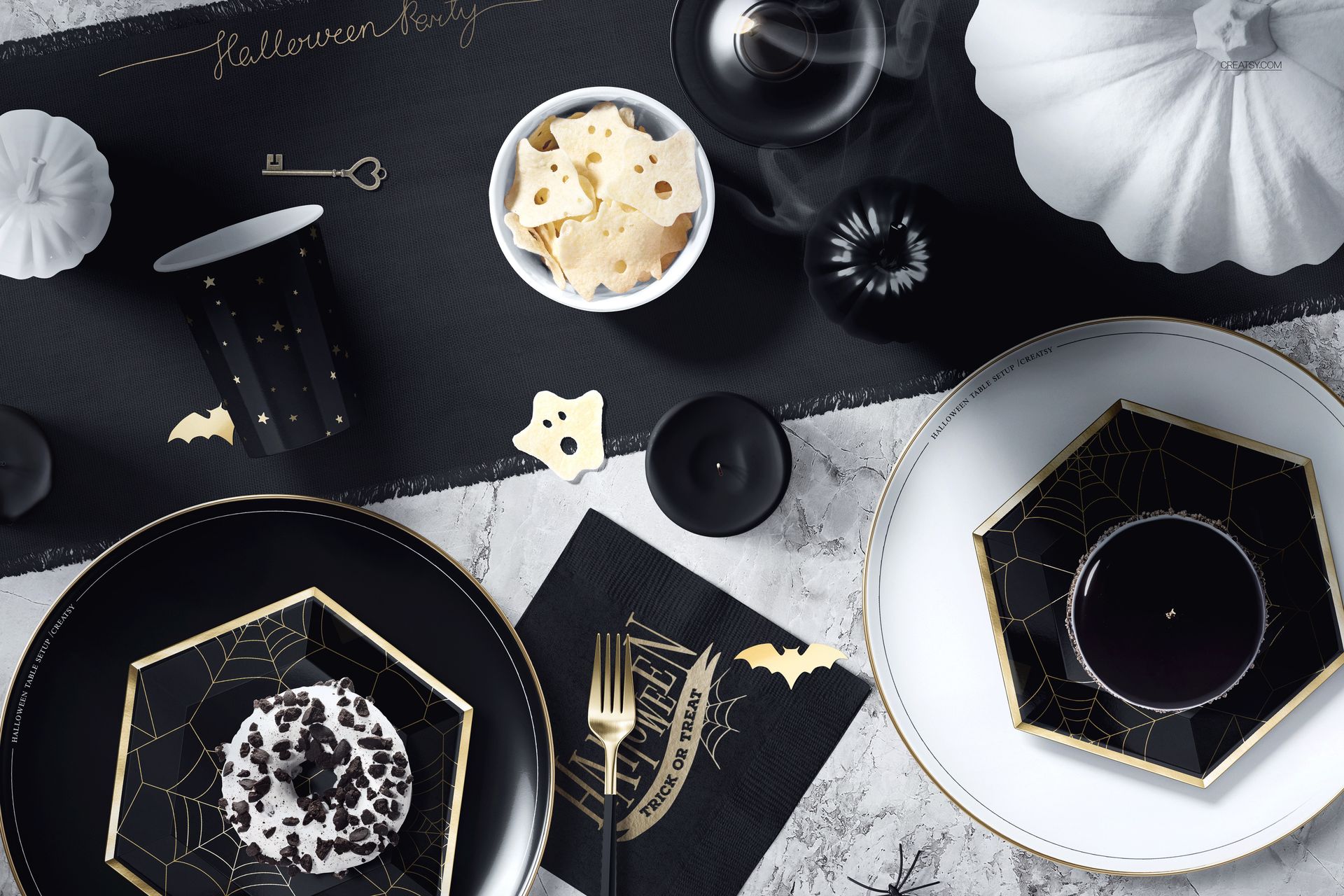 PSD mockup showing a Halloween party table arrangement with monochrome plates, bat napkin, and spooky decorations.