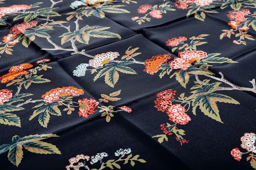 Mockup of a silk scarf featuring a botanical design with branches and flowers on a dark background, top perspective.