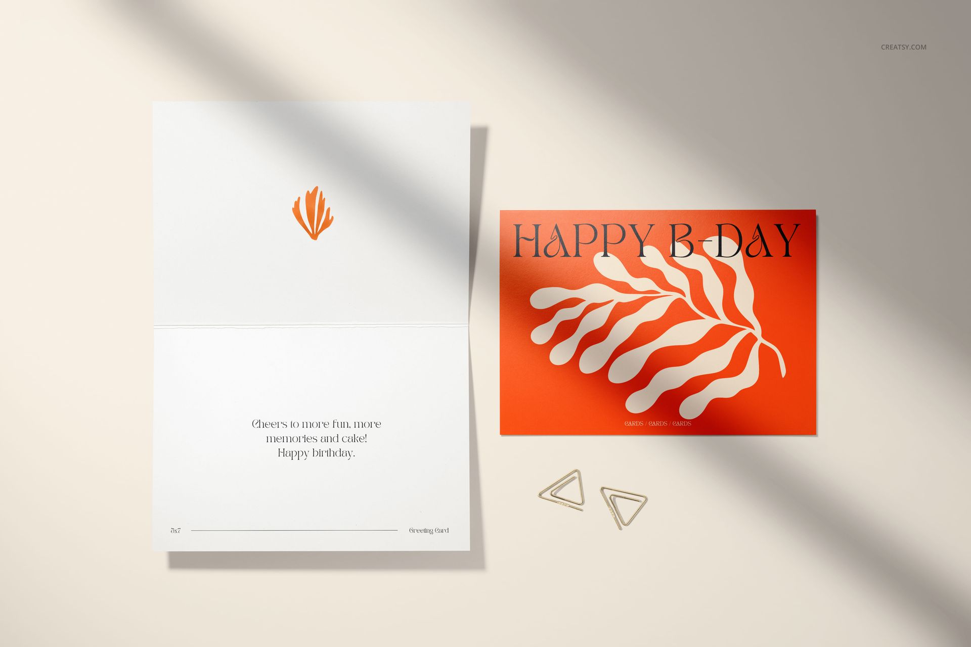 5x7 greeting card mockup featuring an open card and orange envelope with white leaf motif, top view with shadows.