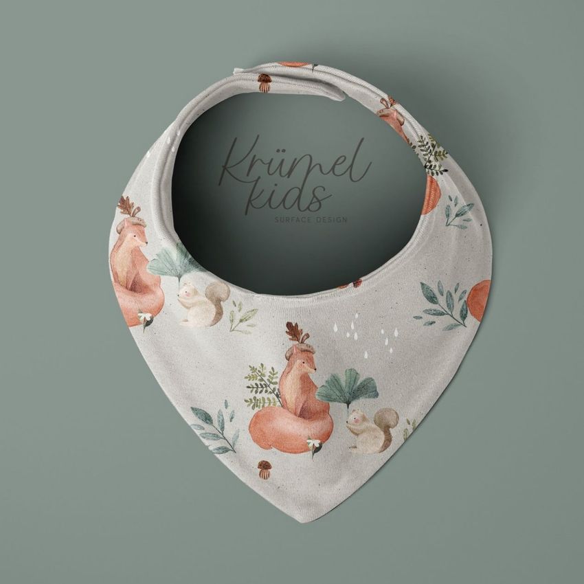 Baby bandana bib mockup featuring a soft fabric bib with a woodland animal pattern, displayed on a muted green background.