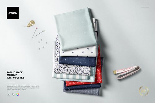 Fabric stack mockup featuring multiple folded textiles in blue, red, and white, with pins and a measuring tape.