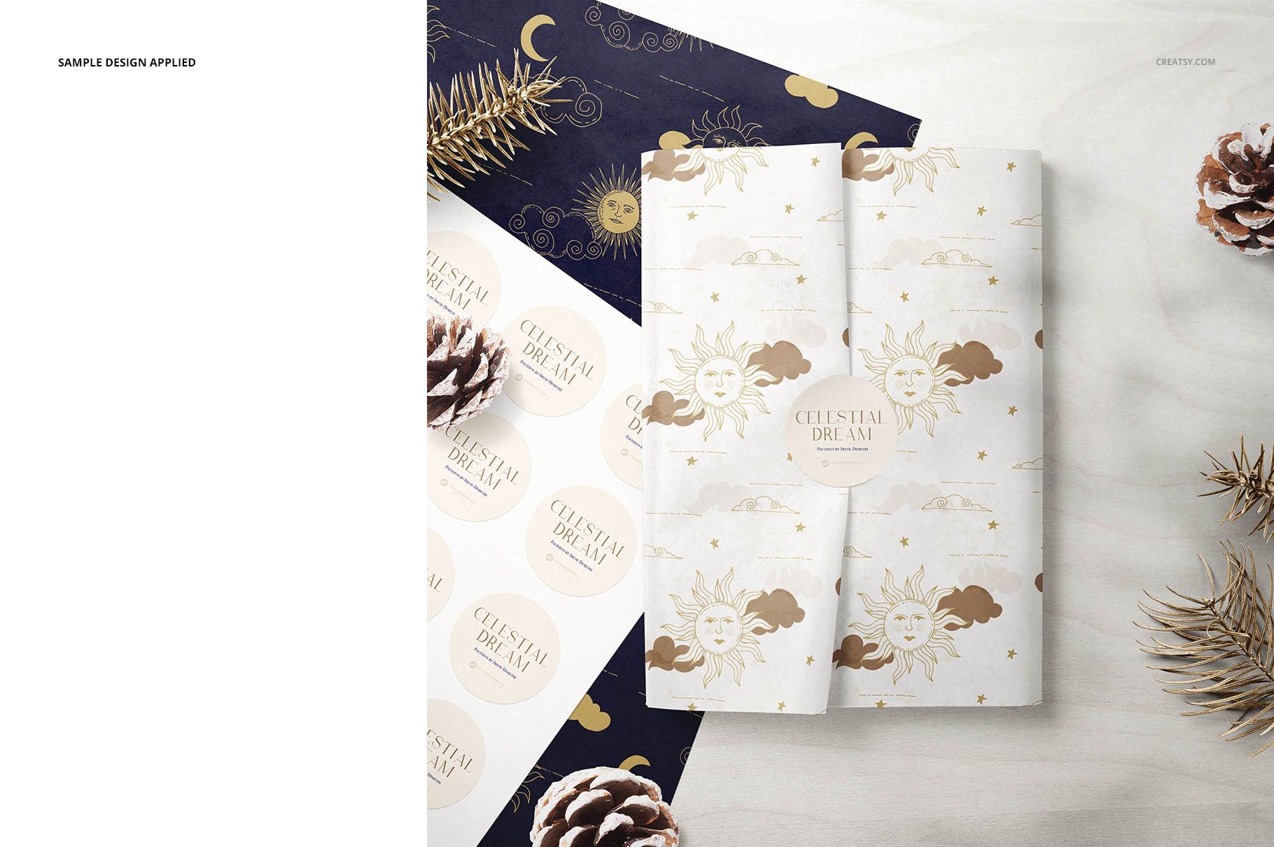 Folded tissue paper mockup with sun and moon design, displayed with pinecones and navy wrapping paper on a light surface.
