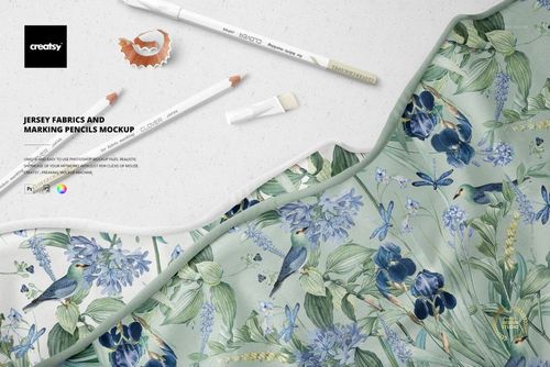 PSD mockup showing jersey fabric with a nature-inspired design, marking pencils, and a pencil shaving on a light background.