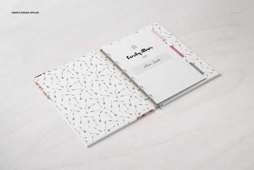 Open family book mockup with metal rings, white cover and patterned inner pages, displayed on light wood surface.