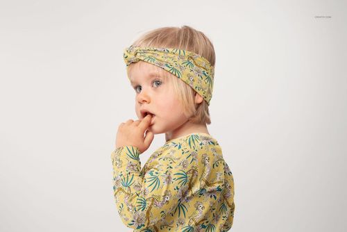 Kids adjustable headband mockup featuring a yellow fabric with whimsical animal and foliage print, side perspective.
