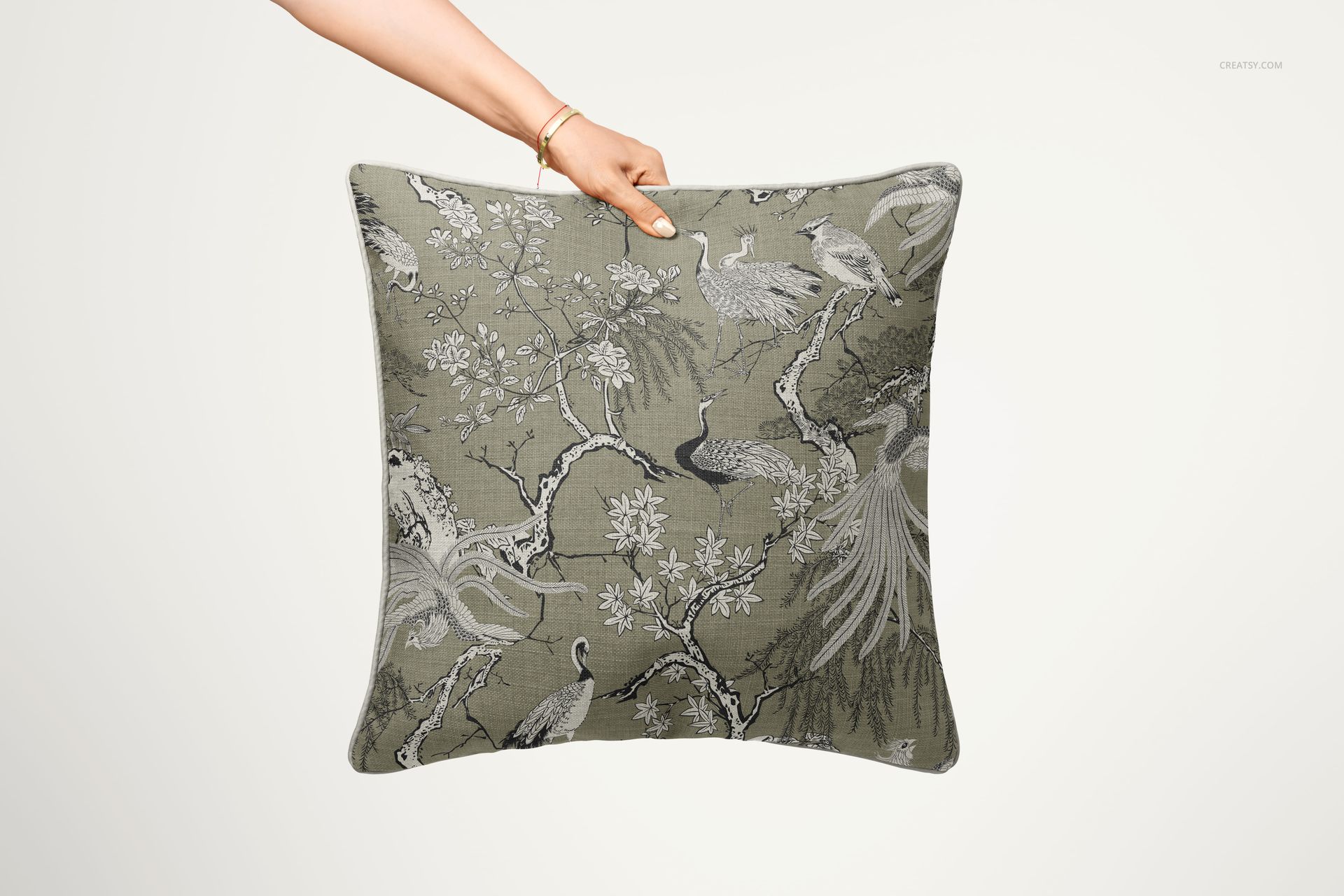 Reversible piped cushion mockup showing a nature-inspired design with cranes and branches, viewed from the front.
