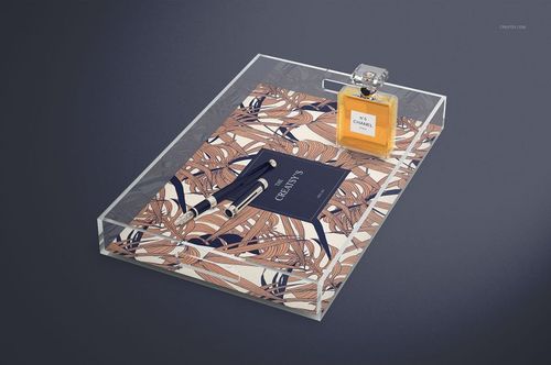 Clear lucite tray mockup featuring a decorative base, pen, notebook, and perfume bottle from an angled top view.