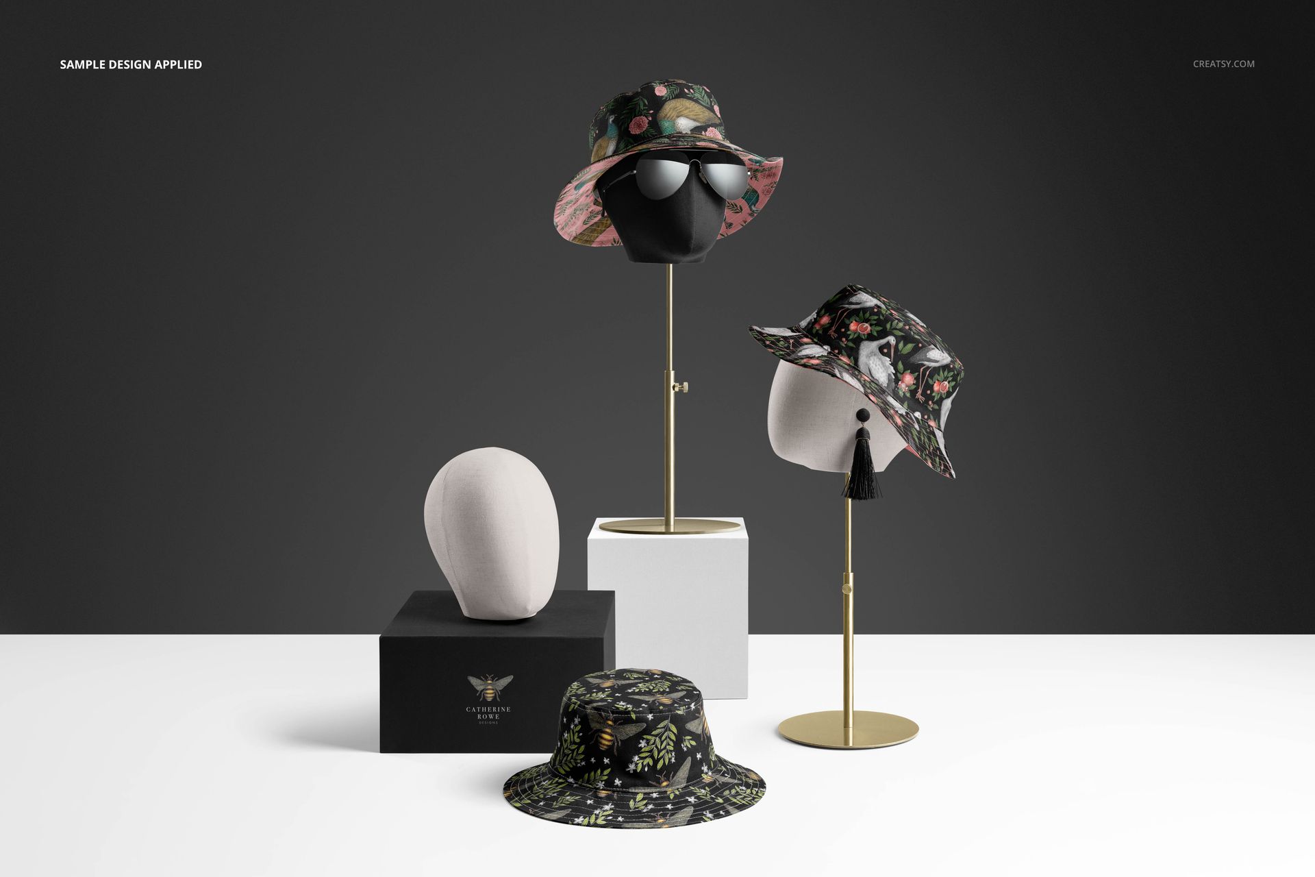Reversible bucket hats mockup featuring botanical designs, shown on mannequin heads and platforms in a studio setting.