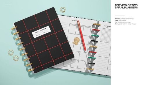 Top view of two spiral planners on a light blue surface, one closed with a black cover and red grid, the other open to a calendar page with a red pen and gold paper clips.