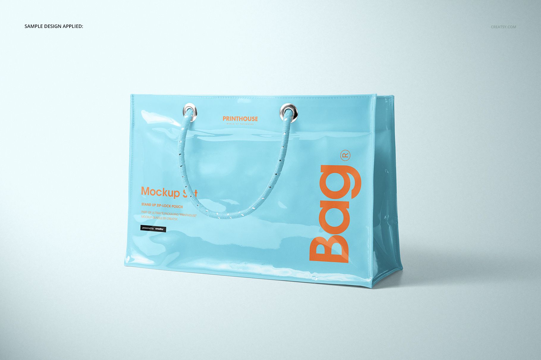 Glossy light blue vinyl PVC tote bag mockup with orange lettering, displayed at an angle on a neutral background.