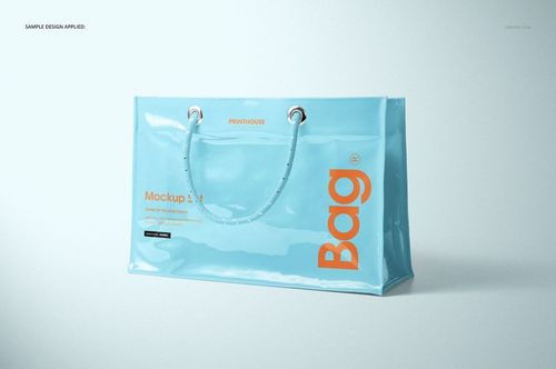 Glossy light blue vinyl PVC tote bag mockup with orange lettering, displayed at an angle on a neutral background.