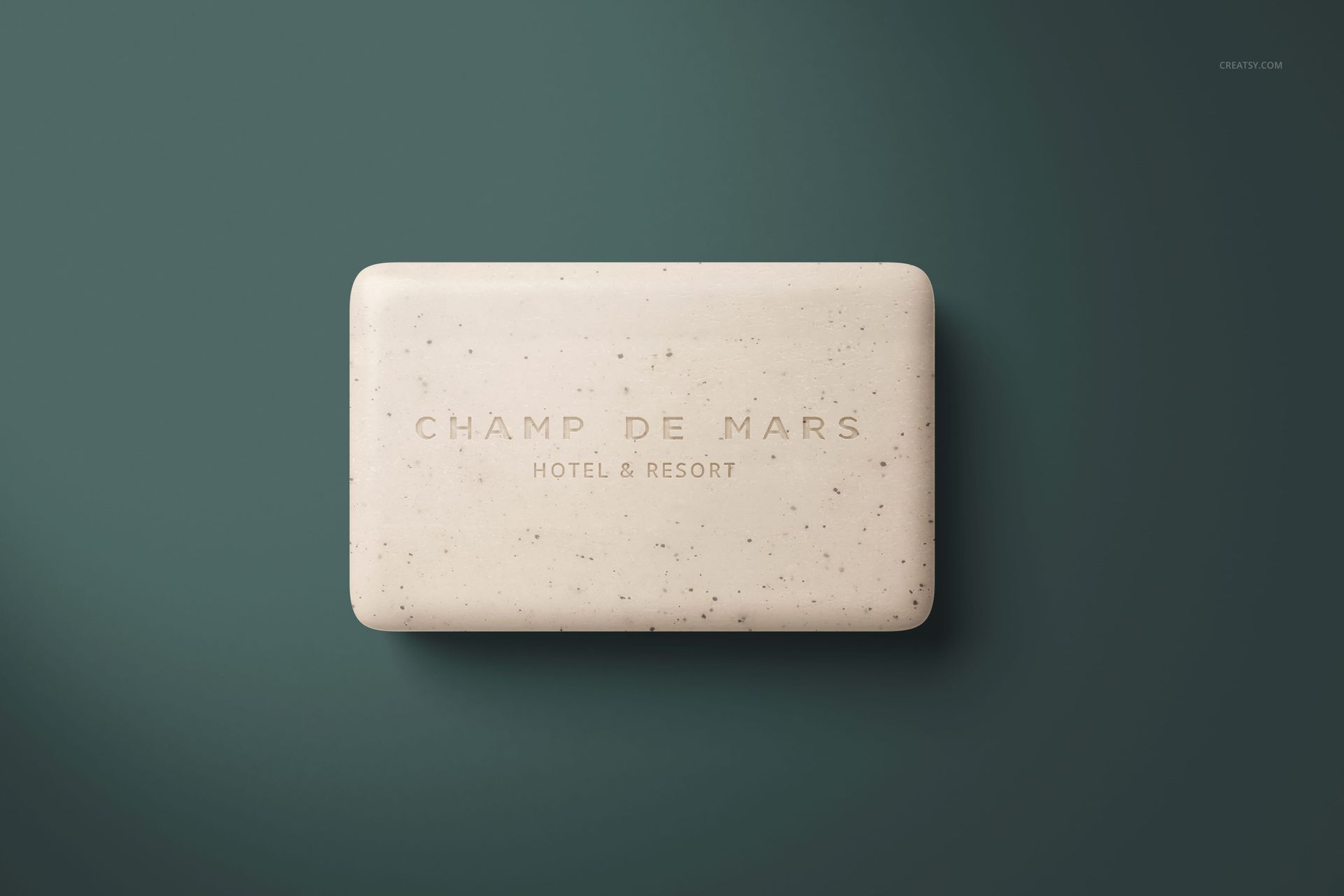 Hotel hand soap PSD mockup featuring a speckled beige bar centered on a dark green surface, viewed from above.