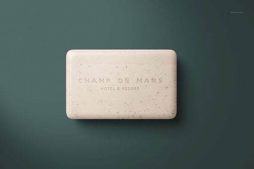 Hotel hand soap PSD mockup featuring a speckled beige bar centered on a dark green surface, viewed from above.
