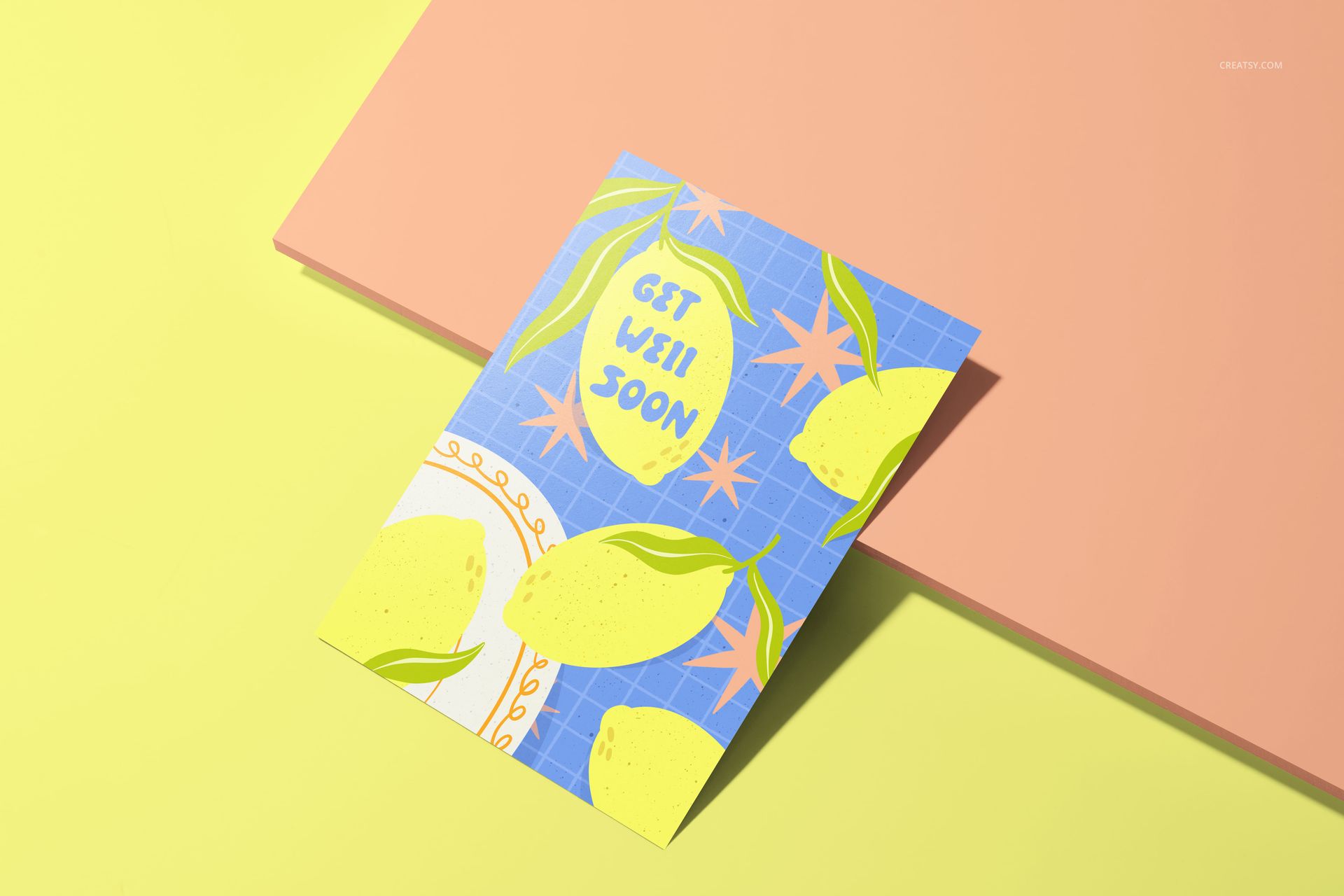 A5 card mockup with a colorful lemon pattern and 'Get Well Soon' text, shown from a top angle on a pastel surface.