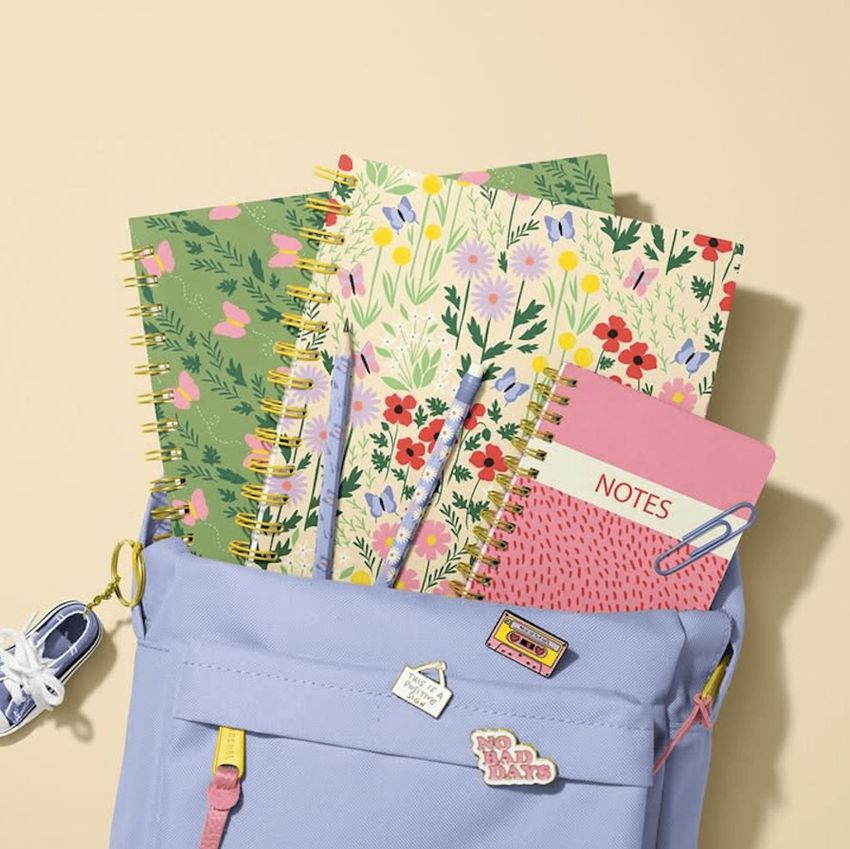 School backpack mockup with spiral notebooks featuring floral covers, pastel colors, and stationery props on a beige background.