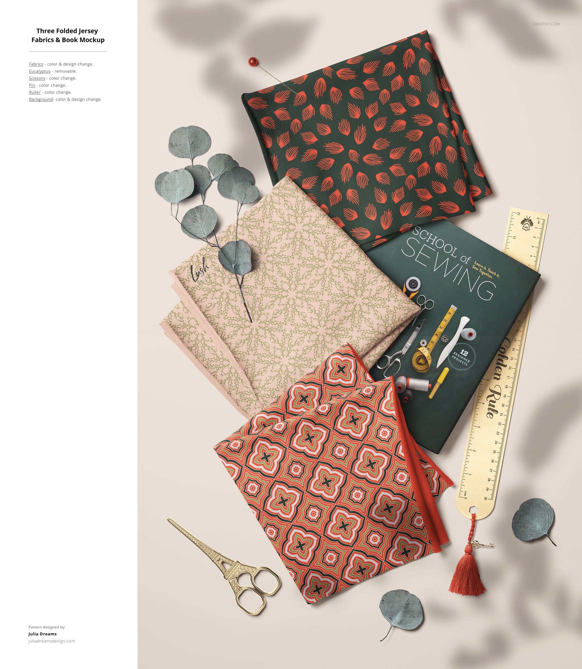 PSD mockup showing stacked jersey fabrics with intricate designs, eucalyptus leaves, and sewing accessories on a beige surface.