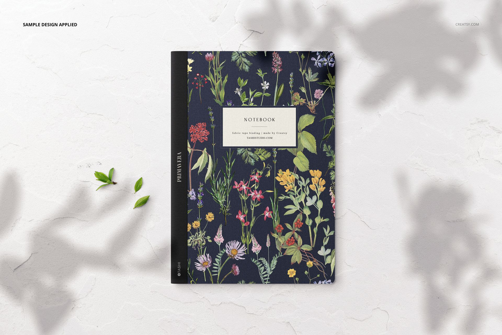 Single notebook mockup showing a floral patterned cover with various wildflowers, viewed from above on a neutral background.