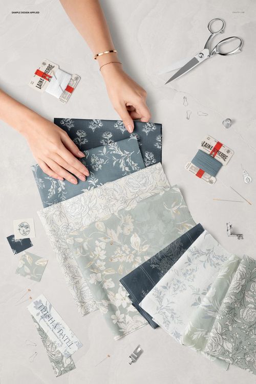 Cotton fabrics in various floral designs displayed flat with sewing tools, labels, and notions seen from above in a mockup.