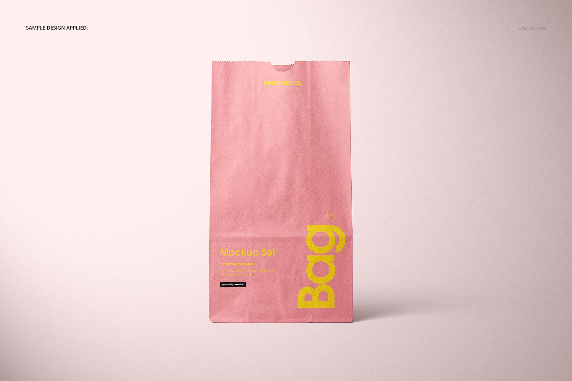 Single pink paper lunch bag mockup displayed vertically, with yellow lettering and a soft shadow on a pale background.