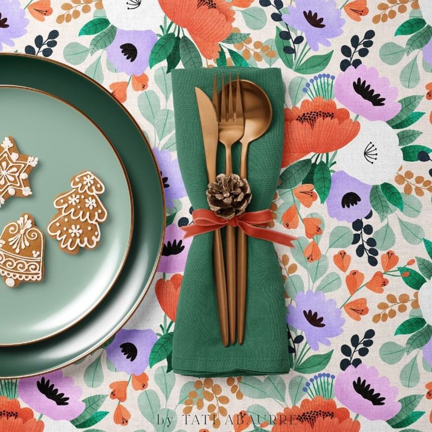 Plate, napkin, and tablecloth mockup featuring a green plate with gingerbread cookies and gold cutlery on a green napkin, set on a floral patterned tablecloth.