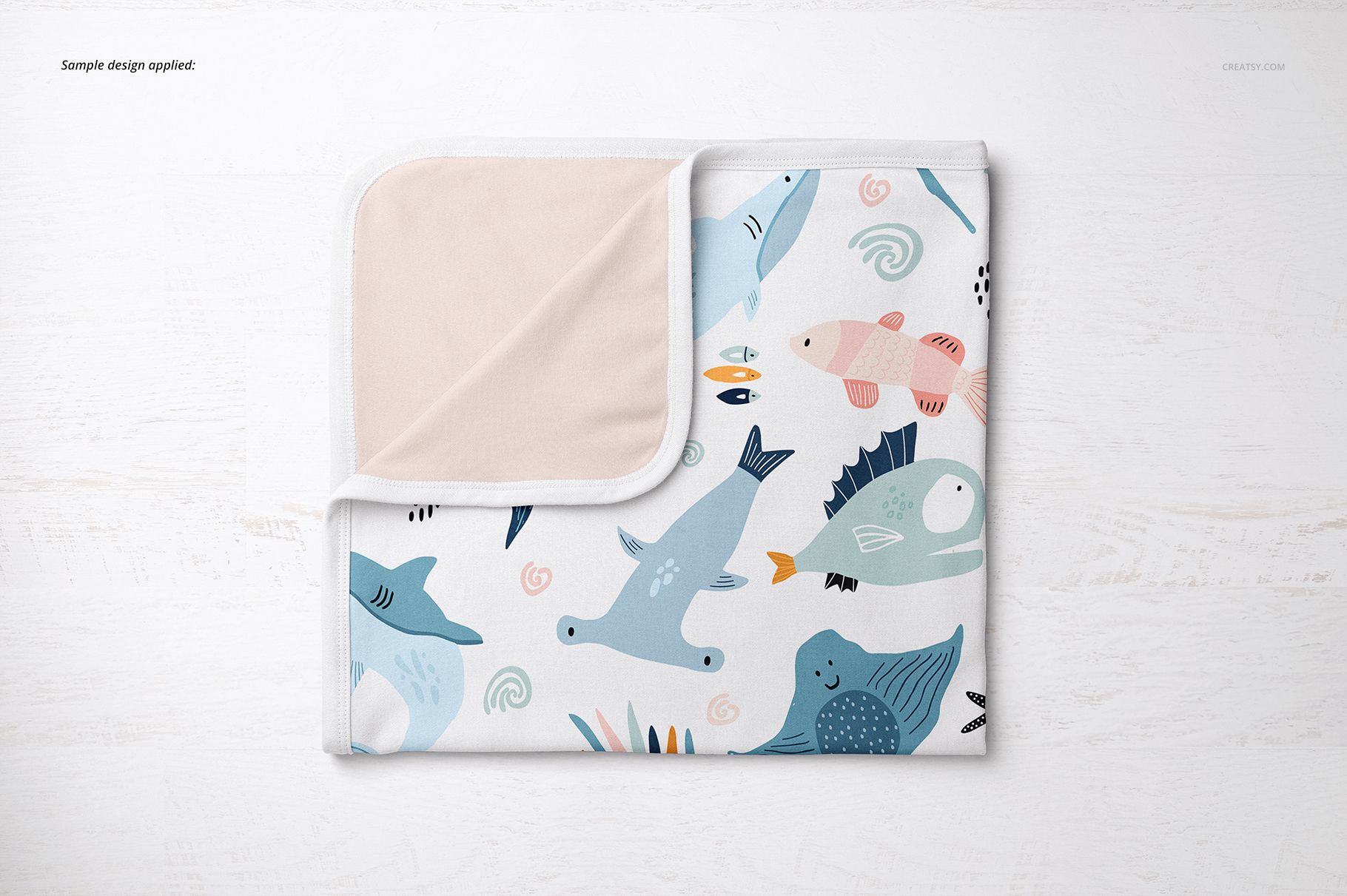 Folded cotton baby blanket mockup featuring colorful fish and sea creatures, top view on white background.