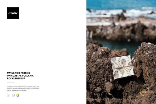 Decorative fabric package tied with twine resting on dark volcanic rocks near the ocean, shown in a mockup scene.