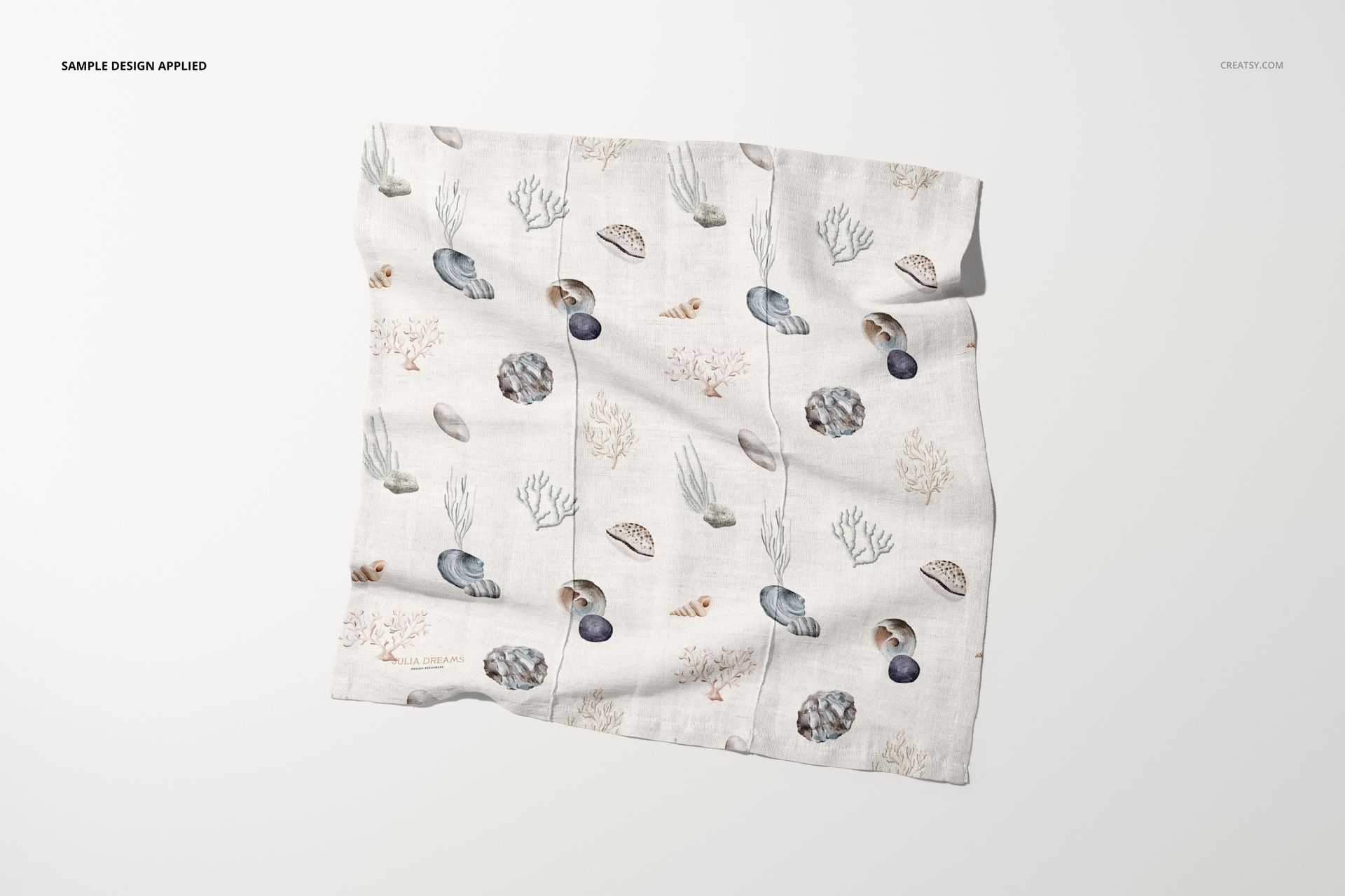 Flat cotton linen napkin mockup showing a neutral background and marine illustrations like shells and plants.