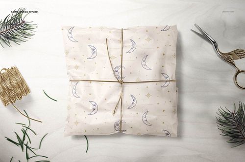 Gift wrapping tissue paper mockup featuring celestial design, surrounded by scissors, twine, and pine branches.