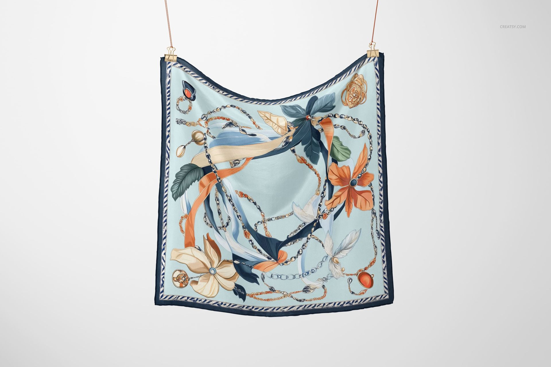 Square silk scarf mockup featuring a botanical and chain design in soft blue and orange, suspended by two clips.