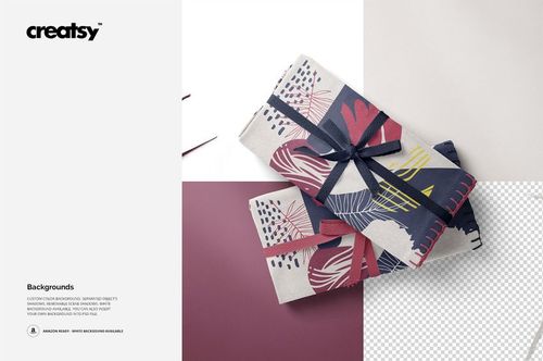 PSD mockup of folded linen fabrics displaying bold leaf motifs in navy, pink, and cream, set on a white surface.