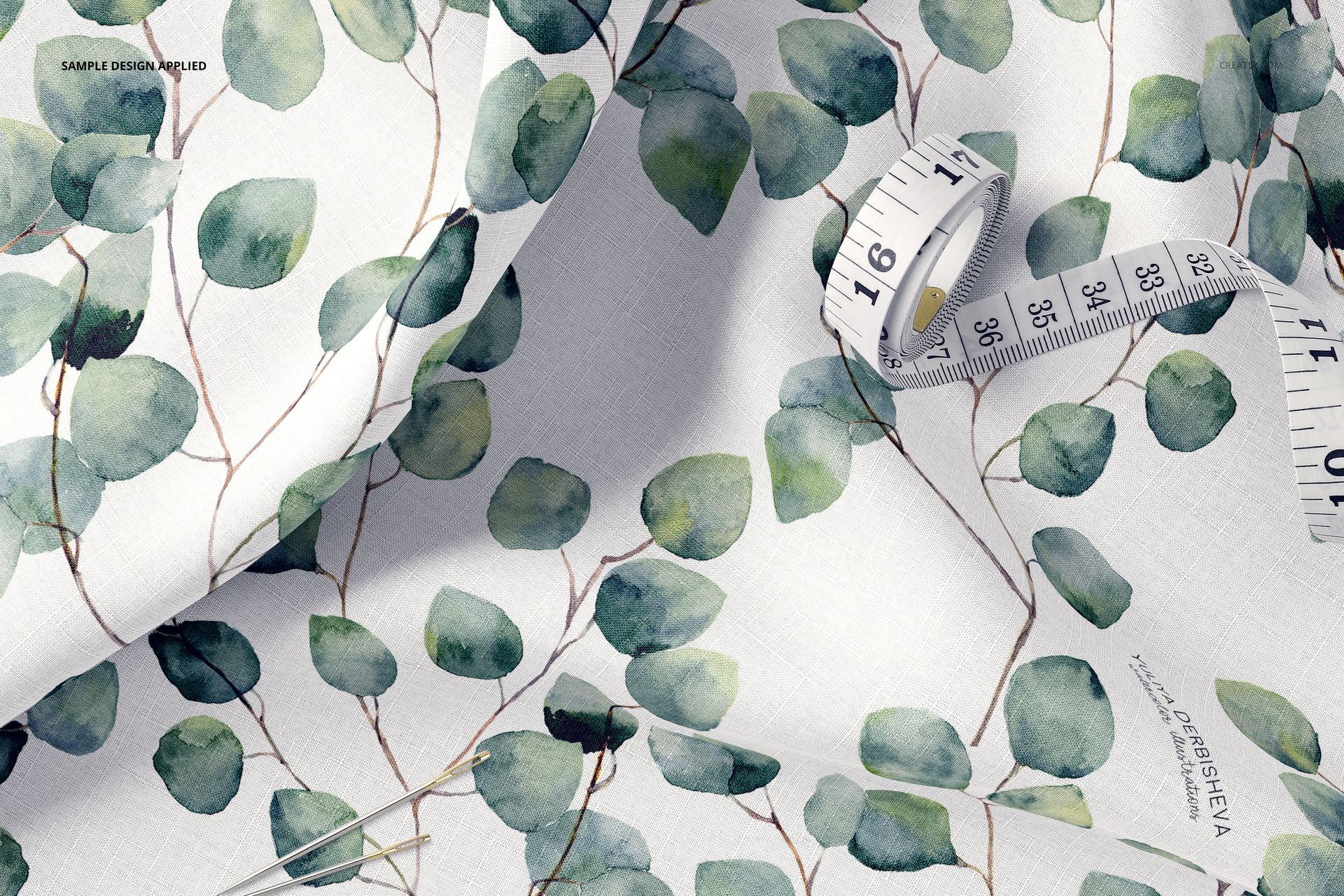 Cotton fabric mockup with leafy green watercolor design, shown in a detailed close-up with sewing tools included.