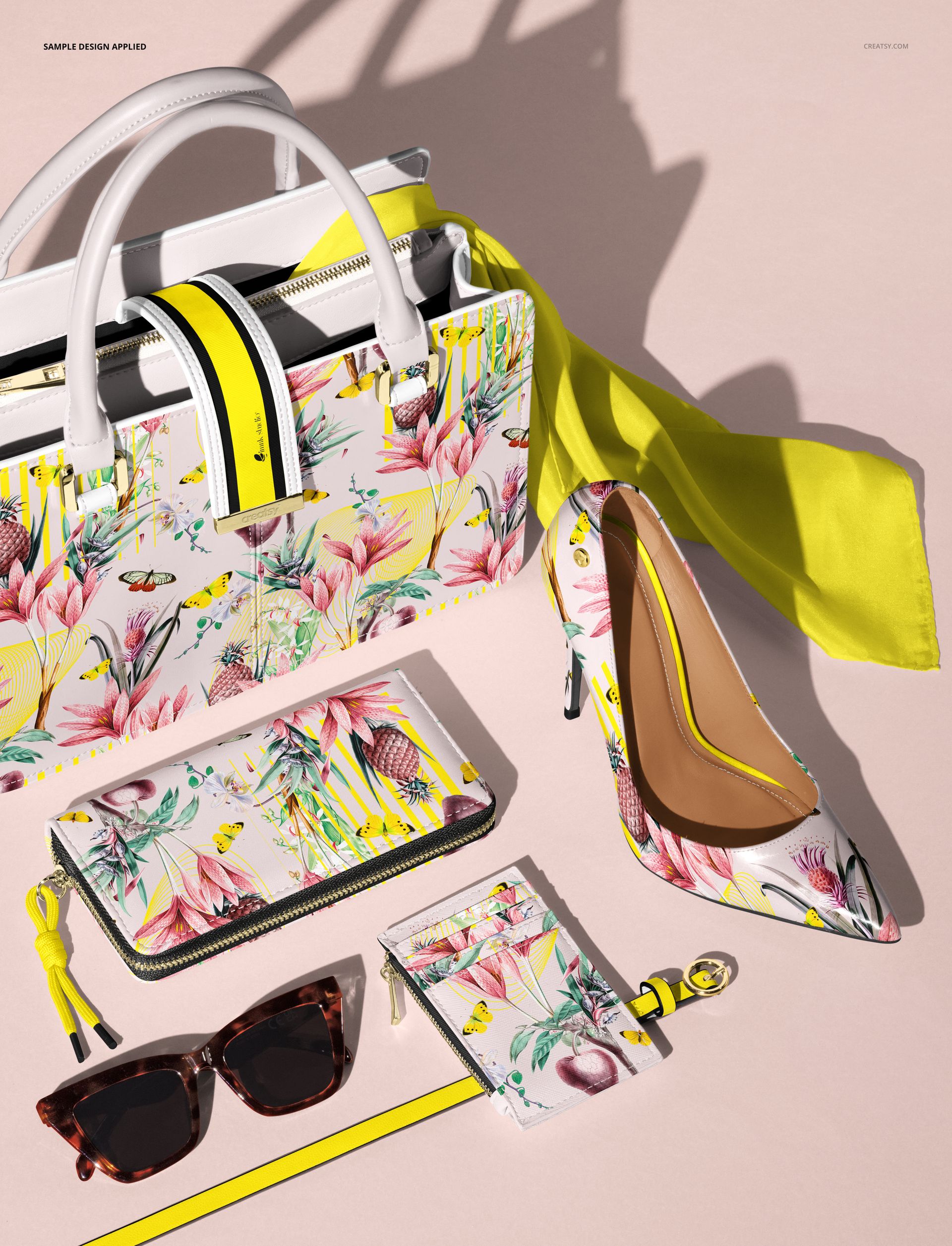Front view of women’s fashion accessories mockup featuring a floral handbag, wallet, cardholder, belt, scarf, sunglasses, and high heel shoe on a light pink surface.