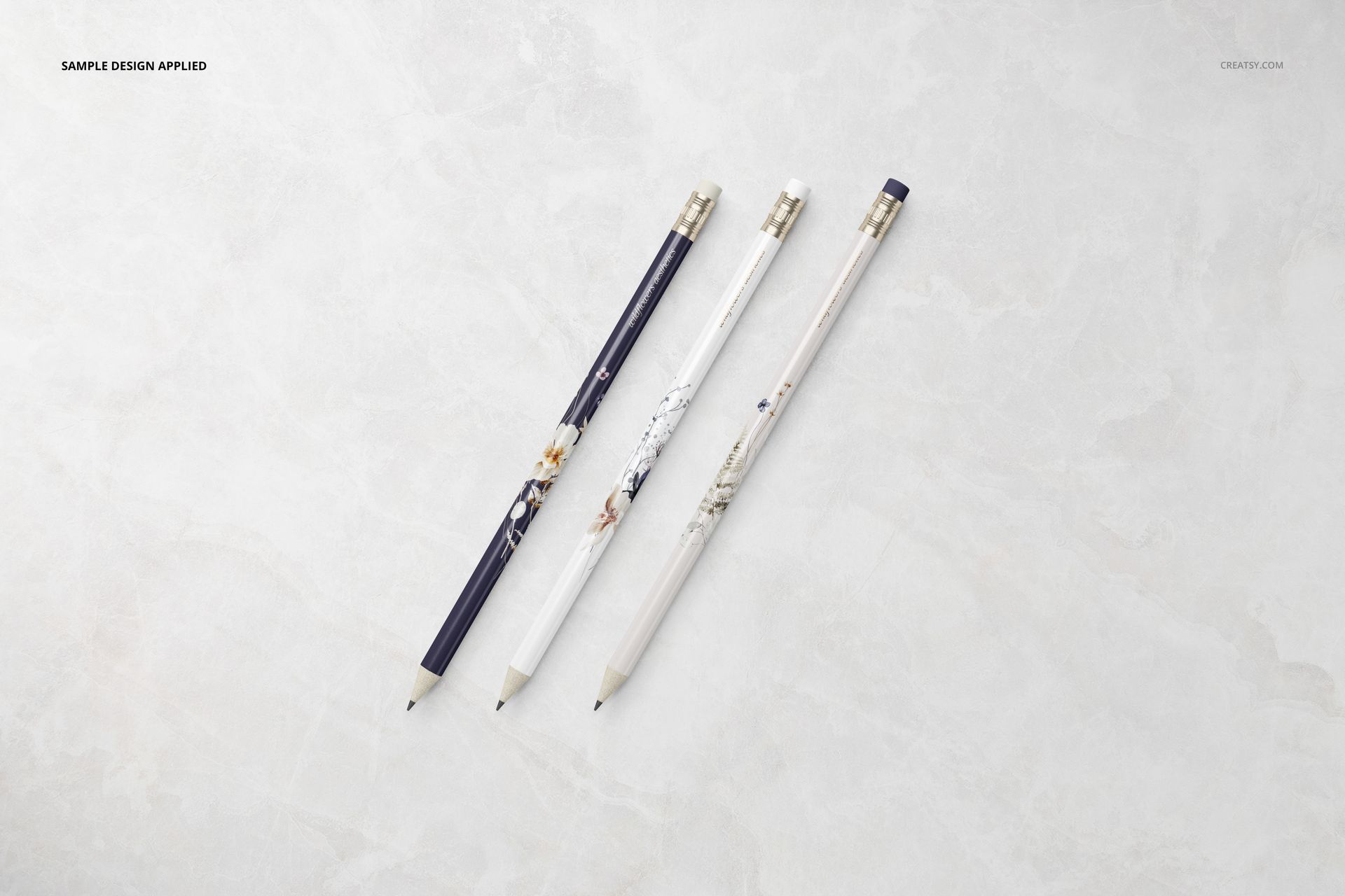 Three pencils with different decorative patterns arranged diagonally on a light marble surface, stationery mockup.