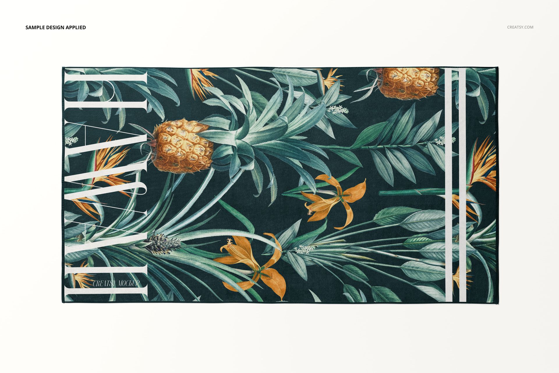 Top view of a beach towel mockup featuring a botanical design with pineapples and foliage on a dark background.