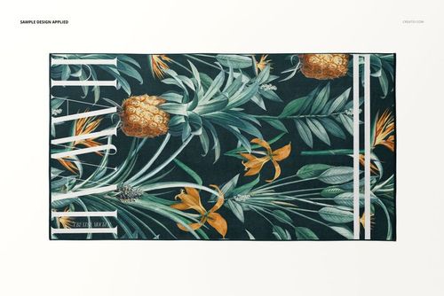 Top view of a beach towel mockup featuring a botanical design with pineapples and foliage on a dark background.