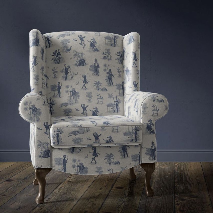 Retro velvet armchair mockup with blue and white patterned upholstery, placed on a wooden floor against a dark wall.
