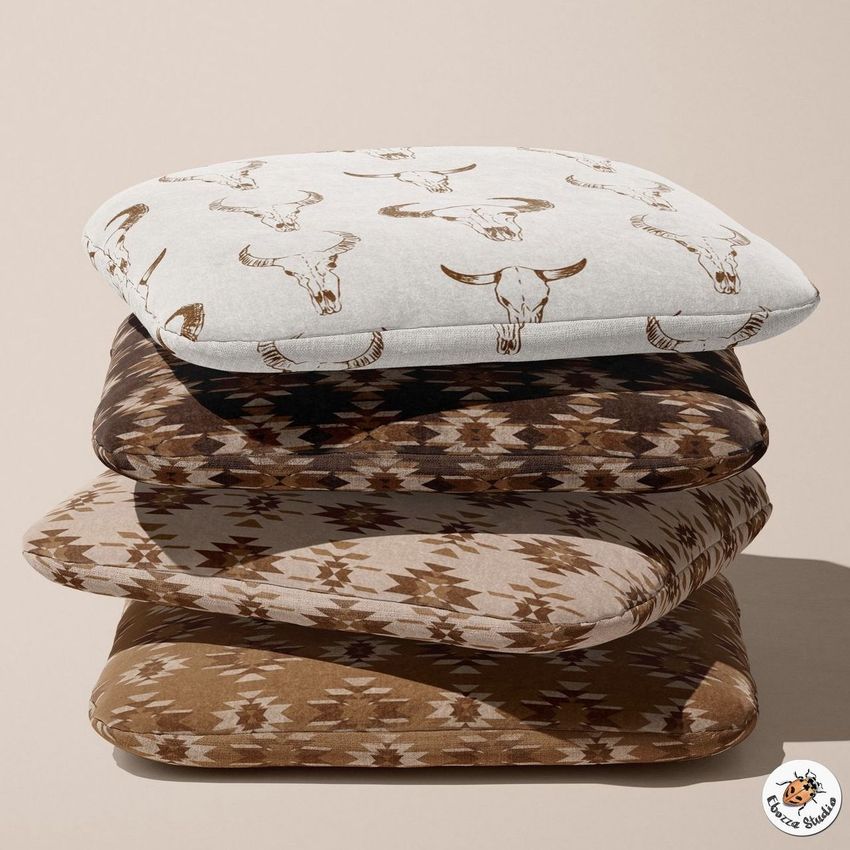 Stack of four rustic chair cushions with geometric and bull skull patterns in brown, beige, and white tones on a neutral background.