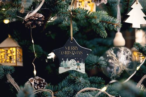 Star-shaped ceramic Christmas ornament mockup featuring a festive winter scene and gold lettering on a tree.