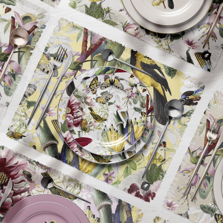 Fringed placemat and plates mockup featuring a floral pattern with butterflies, viewed from above on a white table with cutlery.