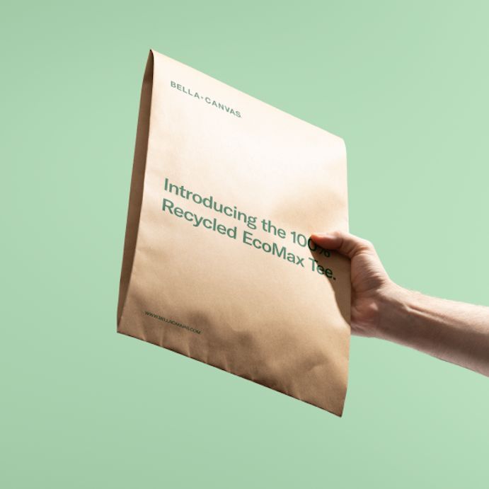Hand holding a kraft mailer mockup against a solid light green background, with green printed text on the front.