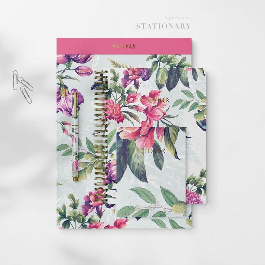 Stationery mockup featuring a spiral notebook, notepad, and pen with colorful floral patterns on a white background.