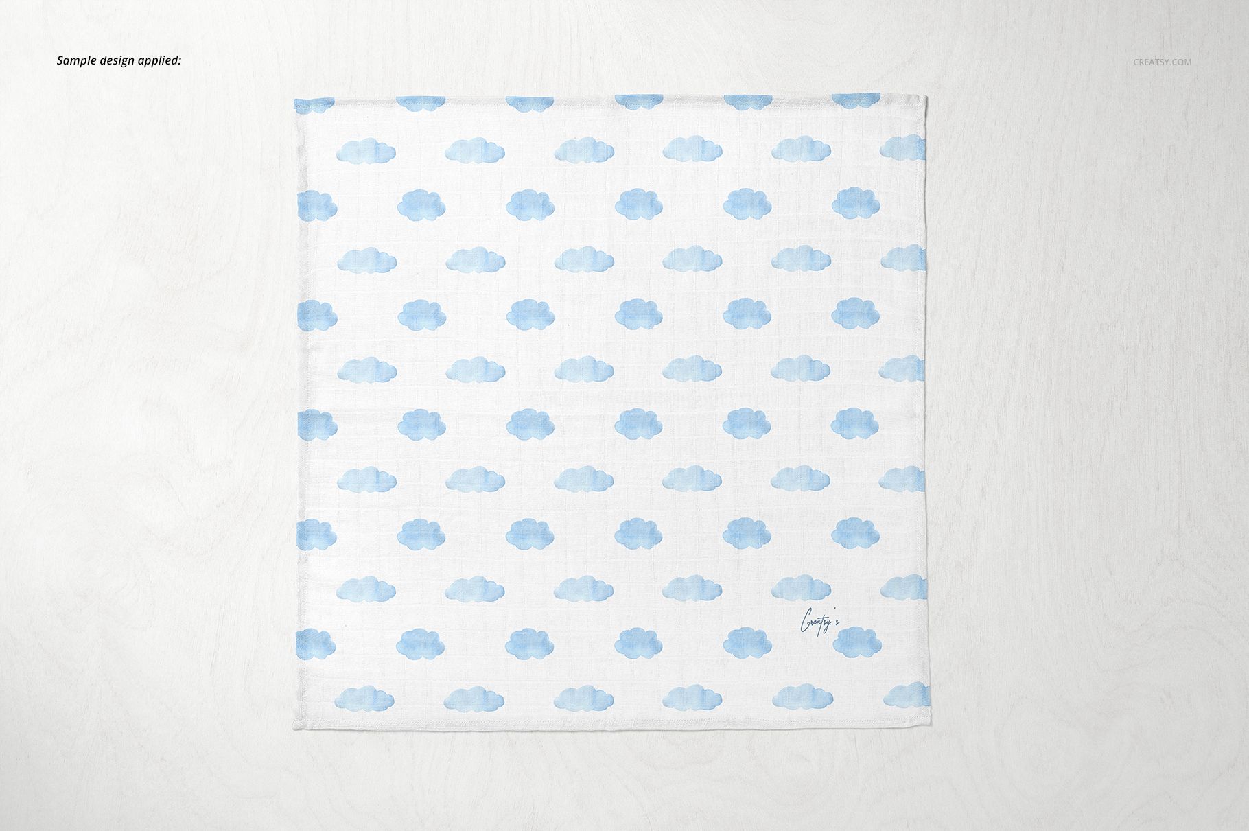 Baby muslin square nappy mockup featuring a repeating blue cloud design, shown from above on a pale background.